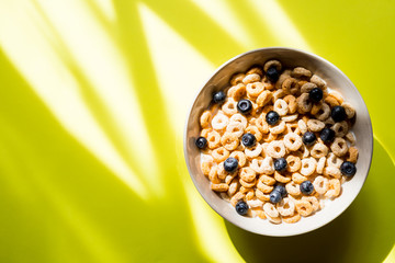 Healthy breakfast with cereal and blueberry.Bowl with healthy cornflakes, milk and berries on yellow table.Tasty circle cornflakes.oatmeal with fruits. Diet concept. Copy space
