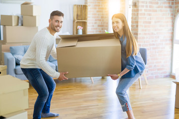 Fototapeta na wymiar Beautiful young couple moving to a new home, holding big cardboard box