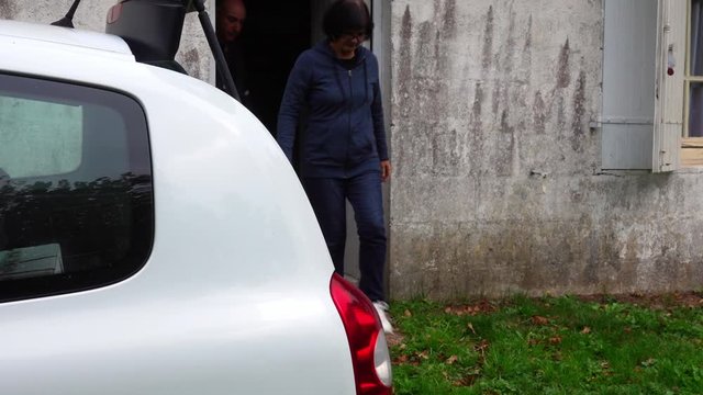 Adult Couple Gets Out Of The House To The Car To Take Things In The Trunk