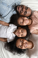 Top view portrait of smiling black family lying on bed