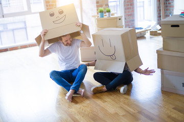 Fototapeta na wymiar Couple wearing funny cardboard boxes with happy faces, moving to a new house, crazy and creative concept