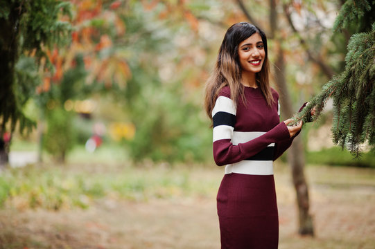 Portrait of young beautiful indian or south asian teenage girl in dress posed at autumn park in Europe.