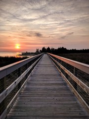 Fototapeta na wymiar Cloudy sunset by boardwalk and water