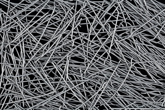Close up, top down view of hooked end steel fibers for concrete structural reinforcement on black background