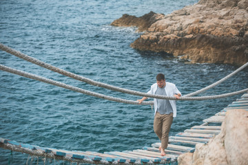 Fototapeta na wymiar man walking by suspension bridge cross sea bay