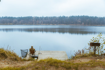 Fototapeta na wymiar fisherman fishing at calm autumn lake