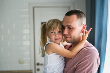Blonde daughter hugs dad tightly at home in room