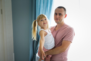 Fototapeta premium Blonde daughter hugs dad tightly at home in room