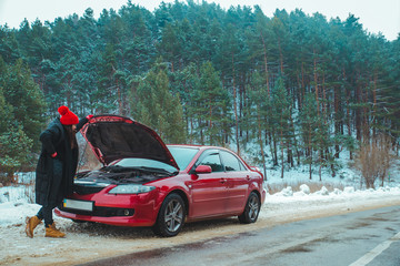 woman looking at engine broken car at winter road side