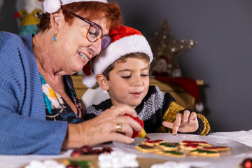 Grandmother and grandson decorating cookies on Christmas time