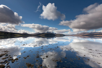 Peaceful panorama at the kyle in Tongue (Scotland) with Ben Loyal snowy peaks at the background. The reflecting cloudscapes dramatize the landscape.