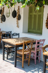 Front view of small cafe exterior. Table and empty chairs outdoor near the white wall. Tourist places. Typical Mediterranean restaurant, a place holidays in the summer