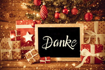 Blackboard With German Text Danke Means Thank You. Christmas Tree With Decoration Like Ball, Gifts And Presents And Snowflakes