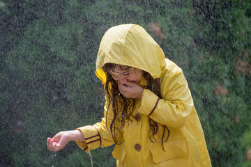 Happy child girl with  rubber boots in puddle