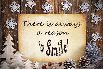Fototapeta na wymiar Old Paper With English Quote There Is Always A Reason To Smile. Christmas Decoration Like Tree, Fir Cone And Snow. Brown Wooden Background