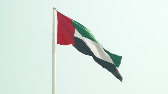 Flag of United Arab Emirates against blue sky in a summer day UAE flag waving in Dubai city , national symbol of UAE. blue sky, uae flag perfect for film, news, digital composition, uae flag day 