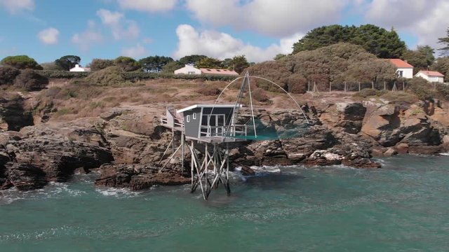 Beautiful drone shot of traditional french fisherman cabin on rocky cliff, blue sky with little clouds and green sea water pornic, france 1-9-19