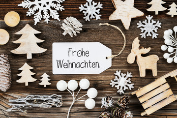 White Label With German Text Frohe Weihnachten Means Merry Christmas. Frame Of Christmas Decoration Like Tree, Sled, Star And Fir Cone. Wooden Background