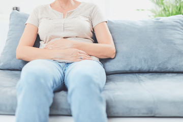 Woman with  stomach issues / problems while lying on the couch.