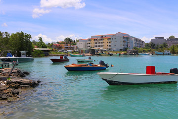 Fototapeta na wymiar Fishing boat anchoring in a bay in front of modern apartment building in Pointe-a-Pitre (Guadeloupe, France)