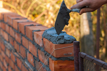 Building a wall with red brick. Working with bricks for building a wall, Construction tools