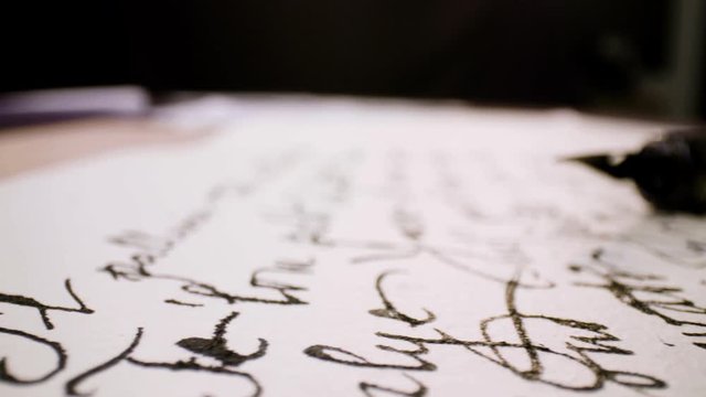 Calligraphy in slow motion. Pan shot of hand written page. Vintage ink pen and quill pen