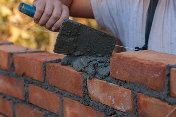 Building a wall with red brick. Working with bricks for building a wall, Construction tools