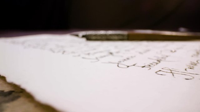 Calligraphy in slow motion. Pan shot of hand written page. Vintage ink pen and quill pen