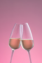 two glasses of sparkling wine on a pink background