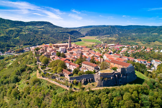 Buzet. Hill town of Buzet surrounded by stone walls in green landscape aerial view.