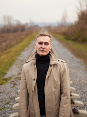 Autumn mood, young guy in a raincoat trench coat underground, street style.