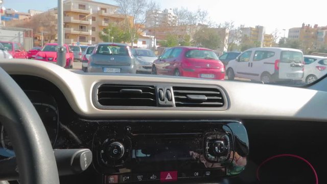 A man close up view of sitting and closing the door of car where others cars are parked in the parking.