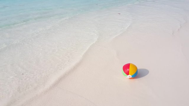 colorful beachball on the sandy beach, rolling around when waves pull it over, Family summer vacation concept