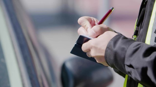 Close up of a police officer's hands writing a traffic ticket