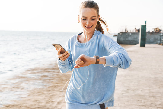 Woman Running Outdoors On Beach Looking At Watch Clock.