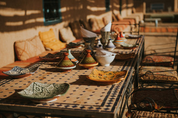 Moroccan meal table settings with ceramic tajines and dishes.