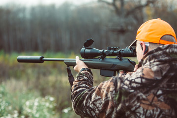 Hunter hold rifle  and aiming to deer.  Hunting optics equipment for professionals. Man aiming target. Leisure ir nature. Aiming skills. - obrazy, fototapety, plakaty