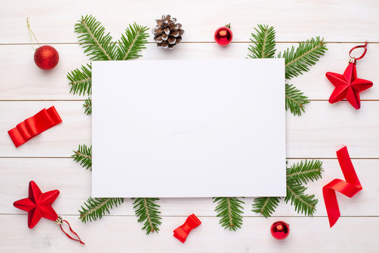 Empty paper for greeting text or logo surrounded with Christmas fir branches and decorations.