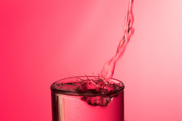 Chorro de agua cayendo sobre un vaso lleno de agua, saltando gotas y chapoteo