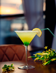 yellow green cocktail with lemon slice on the table