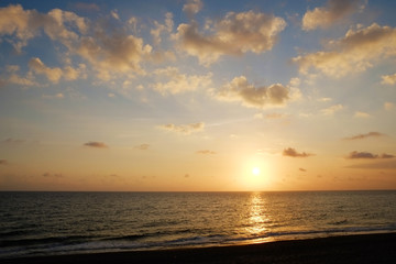 Obraz premium Beautiful seascape of sun setting over calm water with wind patterns and clear blue orange gradient sky without clouds. Ocean view with horizon, background with a lot of copy space for text.