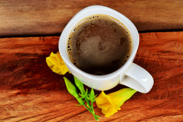 White coffee cup Placed on old wooden floors and natural backgrounds with yellow flowers.