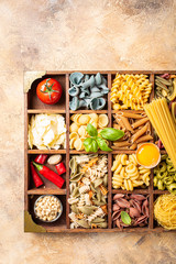 Spaghetti and assorted colorful italian pasta in wooden box. Healthy food background concept. Flat lay, top view.