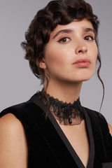 Close-up shot of a brunette lady with a black lace choker with a tulle frill and a fabric flower on...