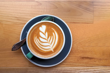 A cup of coffee with latte art on the wooden table