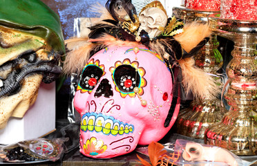 Halloween, pink skull doll with female makeup and a hat with feathers isolated on a blurred background.