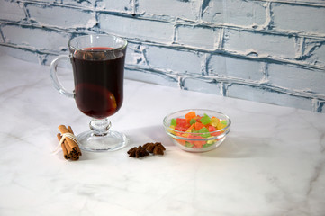 A glass of mulled wine with slices of orange, cinnamon sticks, star anise and dried fruit.