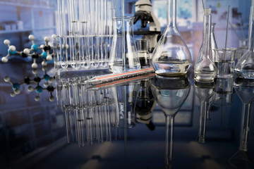 Modern scientific laboratory interior. Laboratory glassware and microscope on the glass table.