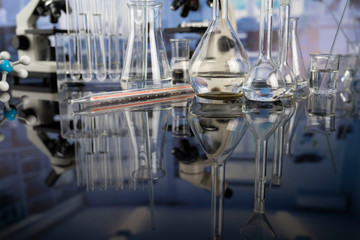 Modern scientific laboratory interior. Laboratory glassware and microscope on the glass table.