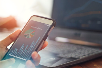 Businessman using mobile smartphone analyzing sales data and economic growth graph chart. Business...
